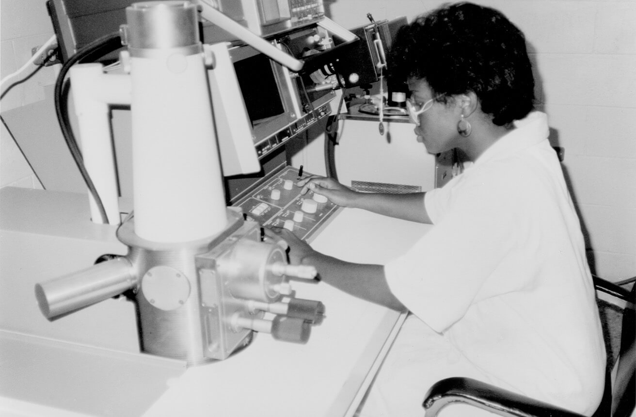 Investigadora jamaicana utilizando un microscopio electrónico.