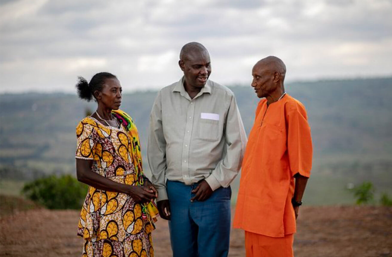 Tres personas conversando en la zona rural de Ruanda.